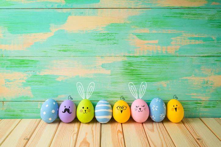 Easter eggs decorations on wooden table over colorful background